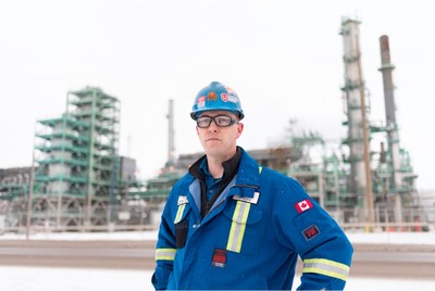 Worker in overalls and hard hat standing outside of a refinery (CNW Group/Unifor)