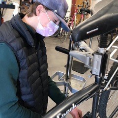 A Project Bike Tech Student Works on a Bicycle.
