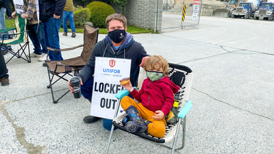 Photo of worker wearing a "Locked Out" sign posing with a young child at a picket line in Victoria, B.C. (CNW Group/Unifor)