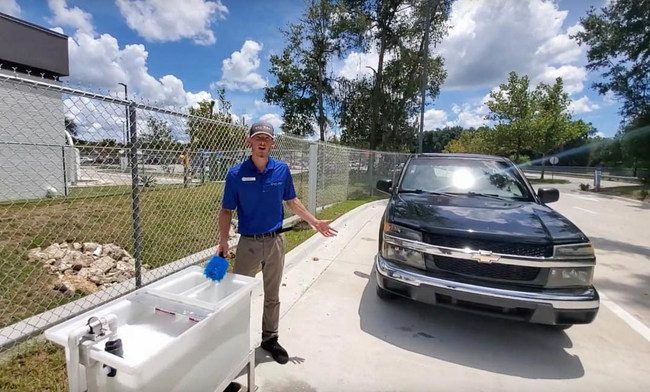 Caliber Car Wash Regional Manager Mitchell Goodman demonstrates how to use two water buckets to better wash off bug splats.