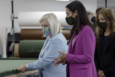 Ferrara Manufacturing COO, Gabrielle Ferrara (middle) walks Senator Gillibrand (left) through the facility's cutting room and inspects American made jersey fabric.