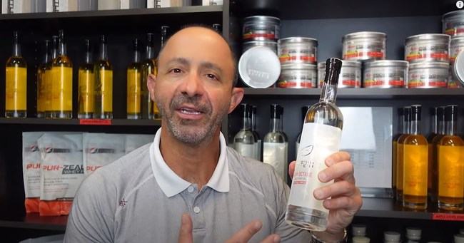 Dr. Derek Alessi East Amherst NY Founder of Strength Genesis Sustainable and Responsible Sports Supplements. In front of Macadamia Nut Oil, High Octane MCT Oil, Raw Organic Apple Cider Vinegar, Omega-3 Cold Processed Fish Oil, Grass-Fed New Zealand Protein.