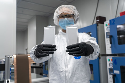 A Solid Power scientist holds two 2 Ah high-content silicon all-solid-state batteries in front of a coated silicon electrode layer. Both were manufactured on Solid Power’s Colorado-based production line using industry standard lithium-ion production processes and equipment.