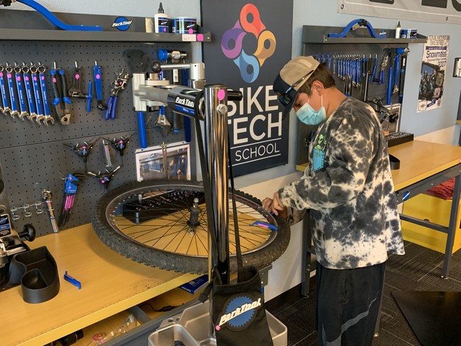 A Project Bike Tech Student works on a Bike in a High School Classroom