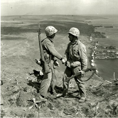 Cpl. Harold "Pie" Keller, right, shakes hands with Sgt. Howard Snyder (KIA), left, as they stand on the rim of Mt. Suribachi on Iwo Jima between the first and second flag raisings on February 23rd, 1945 (Official Army photo, courtesy of Pfc. George Burns, George Burns Collection, U.S. Army Heritage and Education Center).