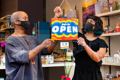 As stores gradually begin to reopen across the province of Ontario, small business co-owners Tannis and Mara Bundi from The Green Jar display a “WE’RE OPEN” sign designed by Toronto artist, Amika Cooper on behalf of American Express Canada, to help welcome people back to Shop Small. Toronto ON. Photo Issue date: June 11, 2021. Photo Credit: Elaine Fancy (CNW Group/American Express Canada)
