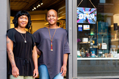 As stores gradually begin to reopen across the province of Ontario, small business co-owners Tannis and Mara Bundi from The Green Jar display a “WE’RE OPEN” sign designed by Toronto artist, Amika Cooper on behalf of American Express Canada, to help welcome people back to Shop Small. Toronto ON. Photo Issue date: June 11, 2021. Photo Credit: Elaine Fancy (CNW Group/American Express Canada)