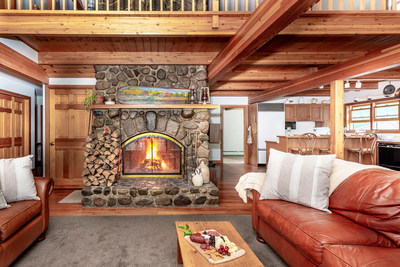 The rustic fireplace features hand-laid stone, serving as a welcoming centerpiece in the main residence’s living area. Exposed wood beams and extensive woodwork is featured throughout the interiors. LakefrontLuxuryAuction.com.