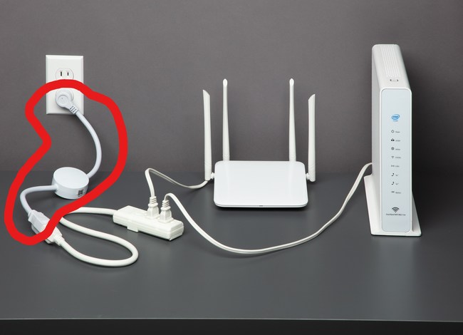 To monitor internet connectivity and automatically reset failed connections, homeowners plug the ConnectSense Internet Rebooter, circled in red, into a wall outlet and extension cord linked to a router and modem.
