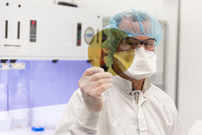 A scientist at SK Siltron CSS holds a silicon carbide wafer produced at the company's Michigan facility. The company plans to expand its Michigan operations to increase production of these wafers, which can be used in power system components for electric vehicles.