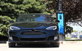 The VoltLock EV Charger pole, featuring the FLO Charger unit, is installed in a parking lot setting. Pictured with an electric vehicle. (CNW Group/StressCrete Group)