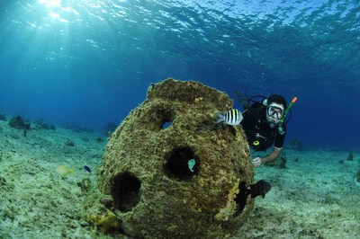 Diver poses with a reef memorial