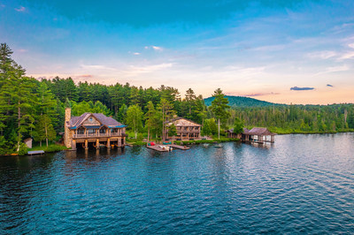 With approx. 900 feet of direct frontage on Upper St. Regis Lake, Camp Limberlost is crafted for those who love the waterfront lifestyle. A two-story boathouse (at left) offers four covered slips, a rolling launch, and storage for three guide boats. The U-shape dock (middle) accommodates multiple boats, and the canoe house (right) includes a launch and covered storage. Learn more at NewYorkLuxuryAuction.com.