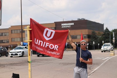 Unifor member with Unifor flag outside of Bombardier Aviation Downsview plant (CNW Group/Unifor)