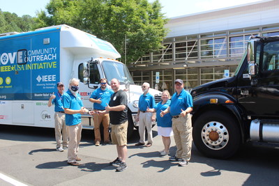 Matt Wood, Lead Tactical Operations Coordinator, CIsco, (black shirt) hands the keys to a Network Emergency Response Vehicle (black truck, at right) to volunteers from MOVE. Cisco donated the vehicle to IEEE-USA for use by its MOVE Community Outreach and Disaster Response Initiative.