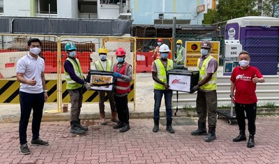 Mr Desmond Tan (Leftmost) with migrant workers at a Pasir Ris construction site, along with host Marcus Chin (Rightmost)