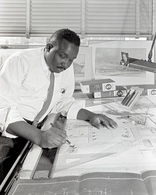 Jessie Strickland reviews architectural plans in his office in 1961. He standardized construction specifications across the agency. Credit: NASA