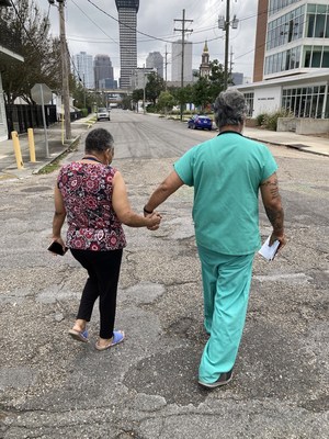 Dr. Vijay Jaligam, JenCare Senior Medical Center, helps a senior during the aftermath of Hurricane Ida walk across a New Orleans street.