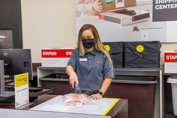 Staples employee preparing returned item to be shipped in a Happy Returns reusable tote.