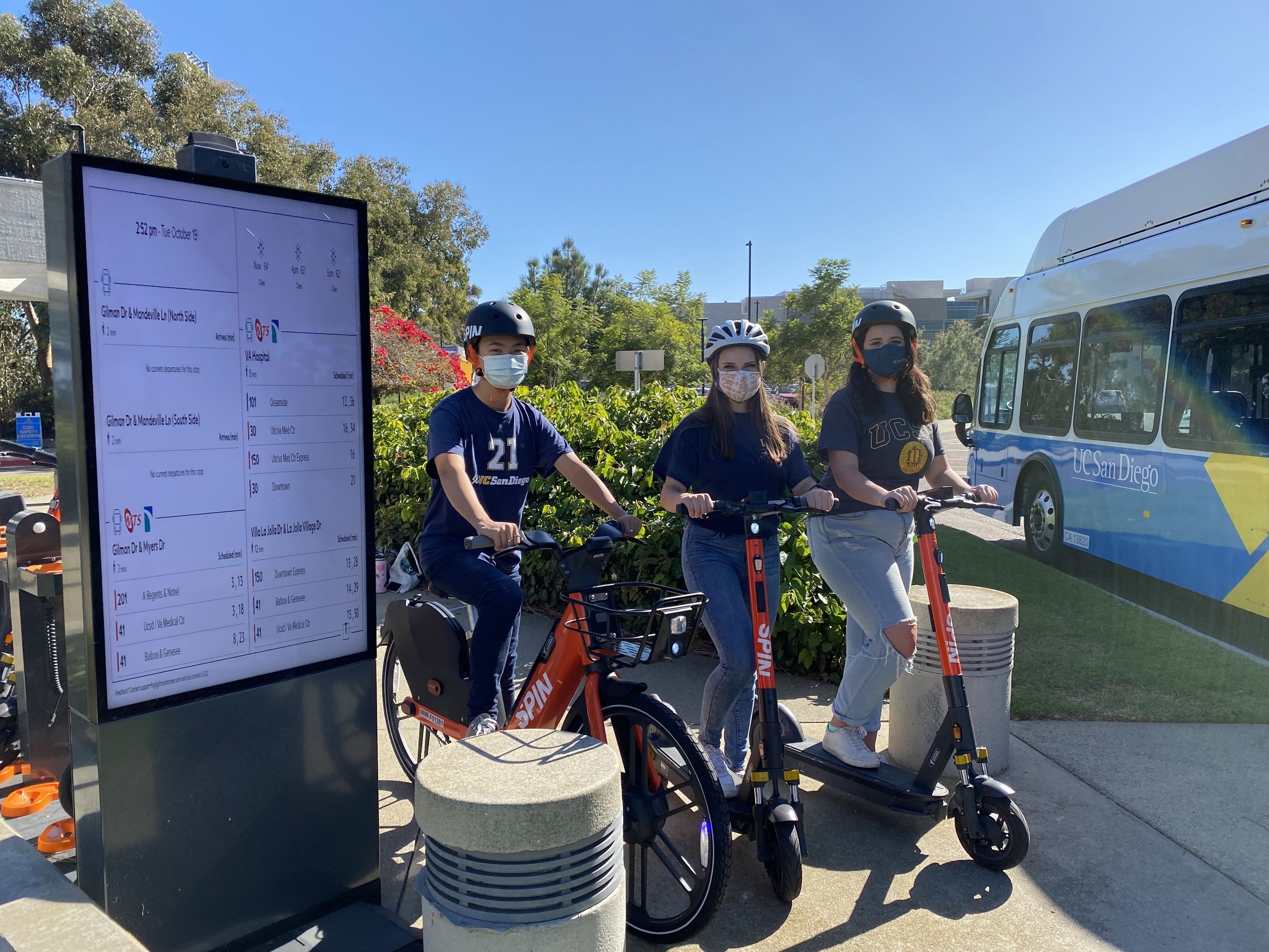 UC San Diego students next to Spin Hub, where a live map of bus locations (powered by TransLoc technology) are displayed.