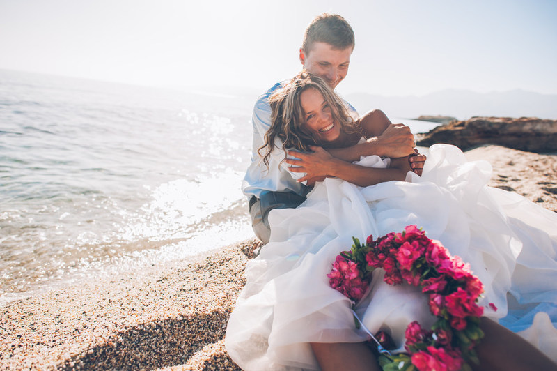 Happy recently married couple embracing on the beach