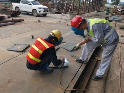 Chinese technician instructs Lao employee in cutting and welding.