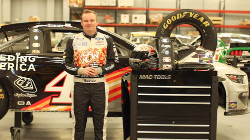 NASCAR Cup Series driver Cole Custer displays auction items from the Stewart-Haas Racing team