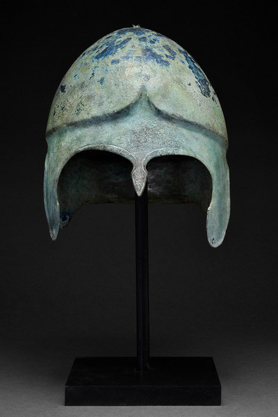 Early Greek Chalcidian hoplite bronze helmet, circa 550-450BC. Expressive form with deep crescentic cheek-guards, small teardrop-shape nose-guard, carefully cut-out eyes with brows in ridged relief, flaring neck-guard. Of a type still in use by soldiers in the time of Alexander the Great. Museum quality. Provenance: a collection of Roman and Greek arms and armor formed in the late 1970s/early 1980s; property of a London gentleman. Estimate £45,000-£85,000