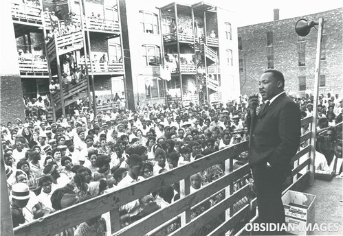 Dr. Martin Luther King Jr. addresses residents in an alley behind an apartment building on Chicago's West Side. King came to Chicago in 1966 to challenge slum conditions and racist policies. This historic moment was captured by legendary photographer John Tweedle, the first African American photographer to be hired by a major metropolitan daily newspaper. This and other rare photos of King taken by Tweedle are being offered as NFTs by the Obsidian Collection to be sold in the NFT marketplace