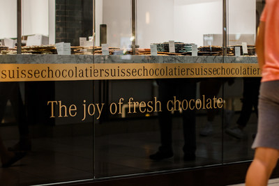 Each Läderach chocolate retail store features its iconic FrischSchoggi (fresh chocolate) counter at the front behind clear glass featuring multiple large slabs of chocolate bark that can be hand-broken and enjoyed for gifting or everyday occasions.