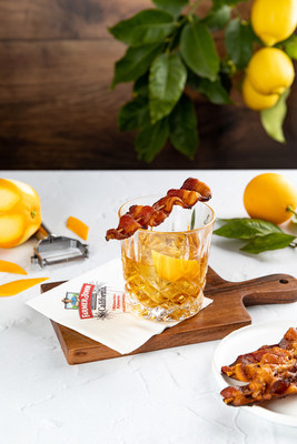The Farmer John Old Fashioned features bacon-infused whiskey, maple syrup, and bitters with savory bacon and a zesty orange peel garnish.