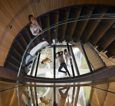 The spiral Oculus Stairs inside the Space Needle, with Guests laying on the glass for views of the tower below. Courtesy Hufton & Crow.