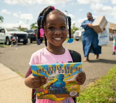 A student receives a book at a Feed the Children event. The nonprofit is distributing more than 275,000 books to Title I schools and community partners across the nation during National Reading Month.