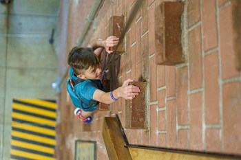 A Fritz's Adventure guest tackles the City Wall, a 48' multi-track climbing experience.