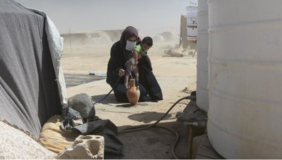 Syrian refugee mother collecting water for her child