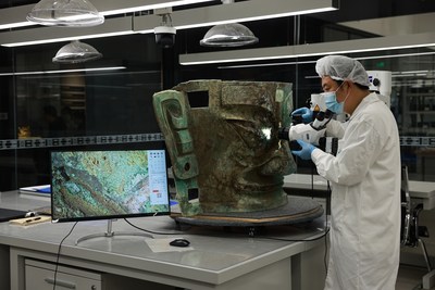 A worker examines a bronze mask unearthed from the Sanxingdui site in Guanghan, Sichuan province. (PRNewsfoto/Sichuan Provincial Cultural Relics and Archaeology Research Institute)