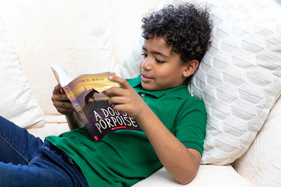 Young boy reading Scholastic book (PRNewsfoto/New Worlds Reading Initiative)