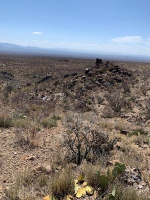Photo 3c is looking west from the JEMI area. The darker coloured rocks cropping out is a large (20 m) peralkaline dyke. (CNW Group/Monumental Minerals Corp.)
