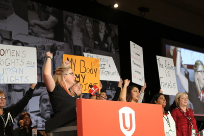 Unifor women on stage at council holding up women's rights signs (CNW Group/Unifor)