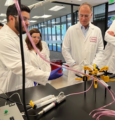 Jan-Dirk Auris (right), Executive Vice President, Henkel  Adhesive Technologies, observes a color-matched adhesives demonstration from Application Engineers Efren Jimenez (left) and Burcak Conley.