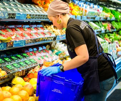 A Natural Grocers' Crew member restocking 100% organic produce in Montrose, CO.