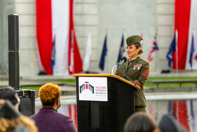 A servicewoman speaks at a ceremony in front of the Military Women's Memorial
