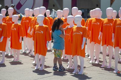 A young girl with one of the 79 child mannequins displayed at Nathan Phillips Square by the nonprofit World Vision Canada, each representing one million children who are trapped in child labour, Toronto, Saturday, June 11, 2022. The event, called #ChildLabour3D Experience, was organized ahead of World Day Against Child Labour, to engage Canadians to stand up for those 79 million children. (CNW Group/World Vision Canada)