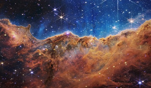 This landscape of “mountains” and “valleys” speckled with glittering stars is actually the edge of a nearby, young, star-forming region called NGC 3324 in the Carina Nebula. Captured in infrared light by NASA’s new James Webb Space Telescope, this image reveals for the first time previously invisible areas of star birth. Learn more about this image: https://www.nasa.gov/image-feature/goddard/2022/nasa-s-webb-reveals-cosmic-cliffs-glittering-landscape-of-star-birth. Credit: NASA, ESA, CSA, and STScI