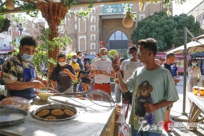 On July 4, a foreign student from Zhejiang Normal University photographed Xinjiang specialties in the International Grand Bazaar pedestrian street