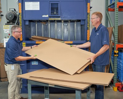 Des employés de CAE Santé chargent des boites dans une presse pour rendre le recyclage plus efficace. (Groupe CNW/CAE INC.)