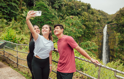 Holoholo Challenge participants taking a selfie in front of a waterfall on Hawaiʻi Island.