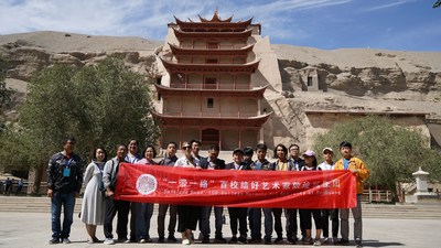 Artists pose for a photo in front of a nine-story pagoda at Mogao Grottoes.