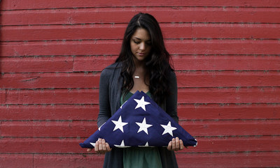 Folds of Honor scholarship recipient, Tayler Garber, holding a folded American flag.