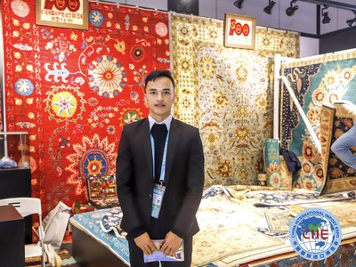 An exhibitor stands in front of the handmade wool carpets displayed at the fourth China International Import Expo held in Shanghai from Nov 5-10, 2021 (PRNewsfoto/CIIE)